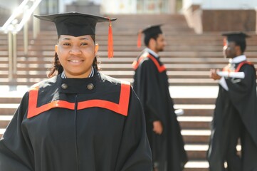 pretty african female college graduate at graduation with classmates