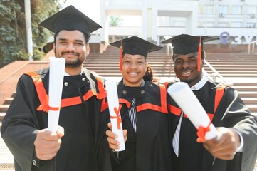Group of multiracial graduate students with diplomas on university background