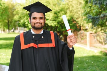 Handsome indian graduate in graduation glow with diploma