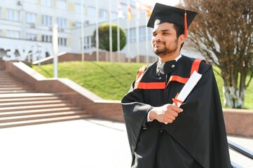 Handsome indian graduate in graduation glow with diploma