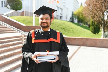 Handsome indian graduate in graduation glow with diploma