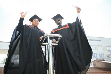 Happy african american couple students in graduation dresses