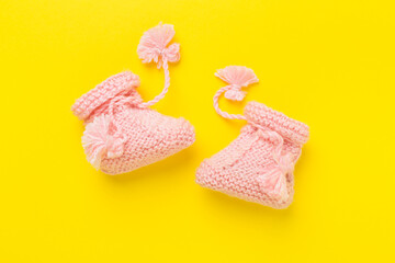 Pink baby booties on color background, top view