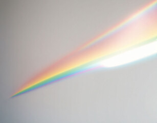 A texture overlay effect of blurred rainbow light refraction for photos and mockups. Organic diagonal holographic flare on a white wall. Realistic natural light effects.