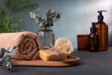A wooden tray with a towel, soap, and a vase of eucalyptus