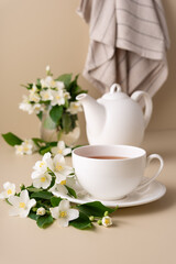 A white tea cup and teapot with a jasmine flowers