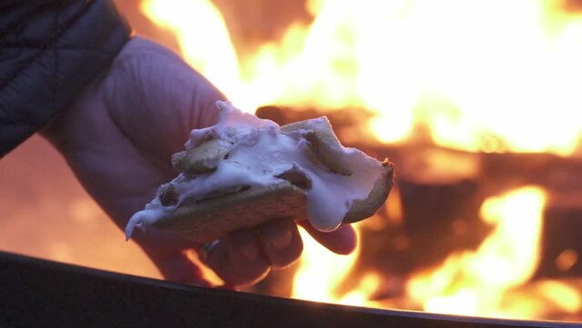 Slow-motion of smore in a hand by a fire pit at night