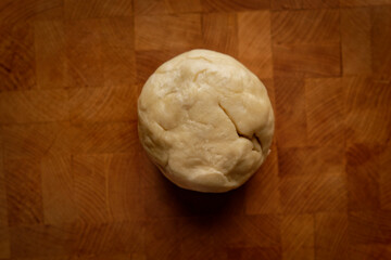 Top view of pie dough rolled into a ball on a wooden board