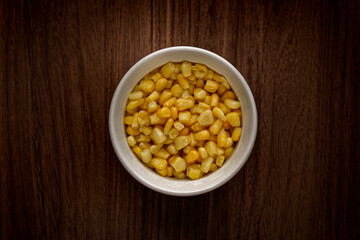 Top view of a bowl of corn on a wooden table