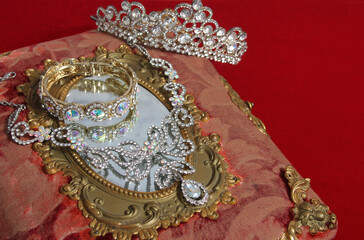Crown and jewelry next to mirror in elegant display