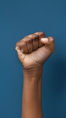 Strong Afro woman's fist against dark blue background, signifying resilience