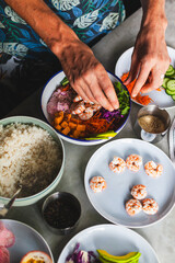 Poke bowl with shrimp prepared by the chef containing white rice, mango, avocado, tomato, etc.