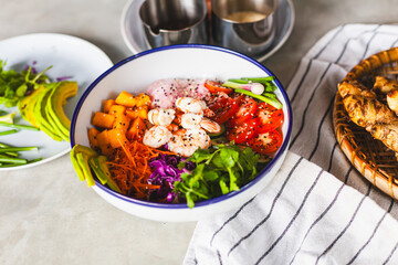 Poke bowl with shrimp prepared by the chef containing white rice, mango, avocado, tomato, etc.