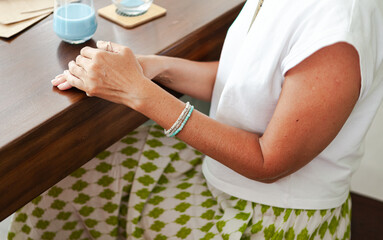 a woman with green bracelet on holding her hands at the table