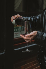 gießt Rotwein in ein Glas