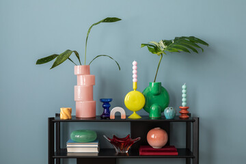 Colorful composition on blue wall with black shelf, design accessories, and decorations vases with...