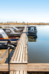 Fishing boats moored at wooden pontoon pier in early morning. Modern motorboats in small docks on...