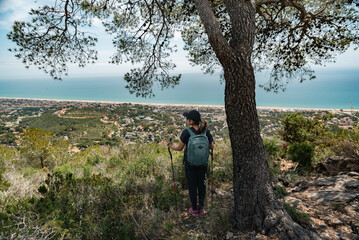 Hiker contemplates the Mediterranean coast from above.
