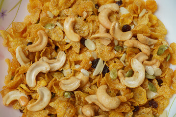 Close-up of cornflakes with cashew nuts, raisins, sliced ​​almonds in white plat