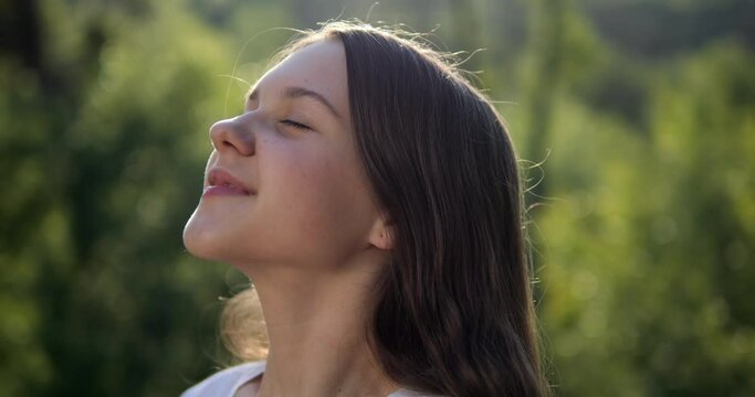 The girl breathes fresh air in nature. Positive mood from good weather and clean environment.