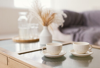 Cups, vase with dryflowers on table