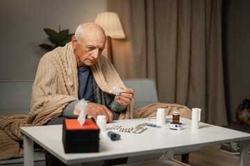 The hands of an elderly man hold pills, ready for use.