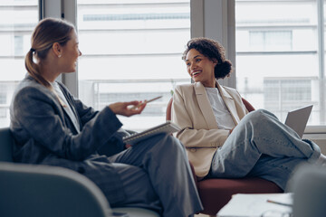 Smiling woman office worker discussing new project with colleague during working day in coworking