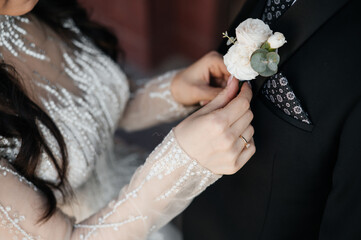 the bride corrects the groom's boutonniere and handkerchief