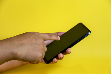hand hold a smartphone  isolated on yellow background
