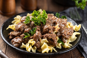 Beef stroganoff with egg noodles garnished with parsley