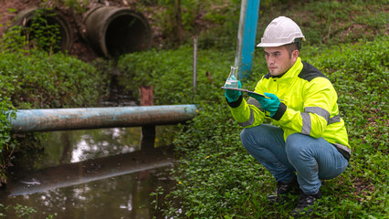 An engineers water treatment sit next to wastewater ponds and inspect the quality of wastewater...