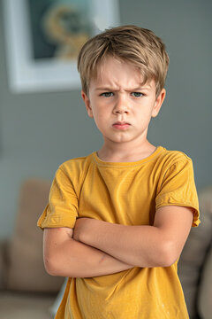 Offended young boy with arms crossed, upset expression towards camera