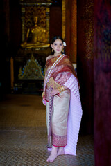 Fototapeta premium Pretty Asian women in traditional Thai dress. Beautiful traditional Thai dresses by Asian Buddhists make merit at the Temple a tourist attraction, a famous place in Thailand.