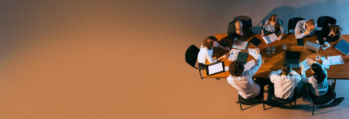 Team of business professionals deeply engaged in strategic planning session, surrounded by laptops, documents, and reports. Concept of business, entrepreneurship, career, teamwork. Banner