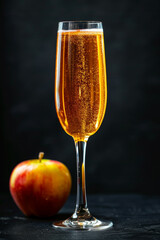 Sparkling Apple Cider in Champagne Flute with Fresh Apple on Dark Background