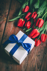 Red Tulips with White Gift Box Tied with Blue Ribbon on Wooden Background