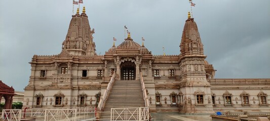The picture depicts Shri Swaminarayan Mandir, which has flags and domes.
