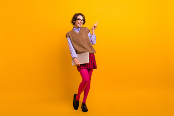 Photo portrait of attractive young woman hold netbook point empty space dressed retro office clothes isolated on yellow color background