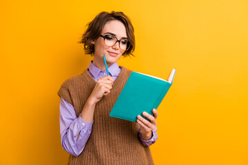 Portrait of clever nice woman in glasses hold pencil write to do list look at book pencil on chin isolated on yellow color background
