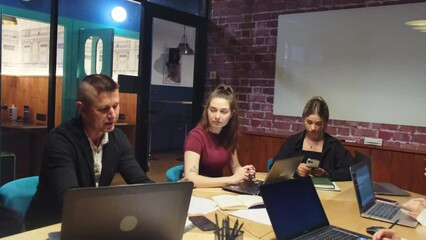 Business staff gathers to discuss completed work in coworking zone. Group of office managers meets with male boss in coworking zone