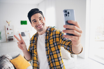 Photo of cool good mood man wear checkered shirt showing v-sign tacking selfie modern device...