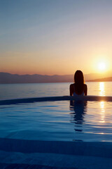 Fototapeta premium silhouette of a person sitting on the beach at sunset