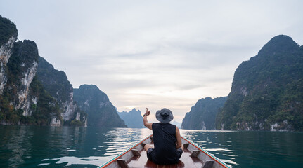 Male tourist sitting on a long-tailed boat, showing left thumb up with a 