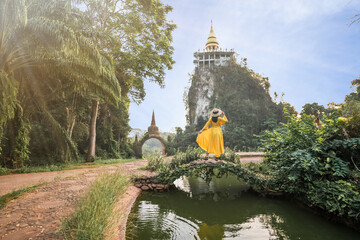 Asian female tourist in yellow dress and hat at The large ancient pagoda arch is beautiful, Khao Na...