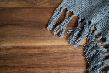 Gray fringe scarf on wooden table, stylish contrast in textures