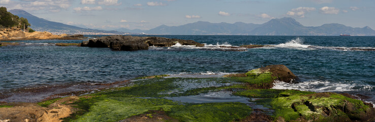 panorama di Marechiaro a Napoli con veduta del Vesuvio e isole campane con onde e rocce in primo...