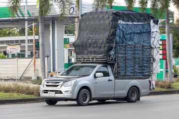 A pickup truck loaded with boxes drives down a city street, Thailand © milkovasa