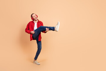 Full size photo of nice young man play guitar leg wear red shirt isolated on beige color background