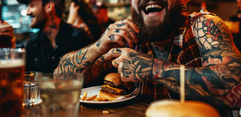 Happy tattooed man eating burger and laughing with friends 
