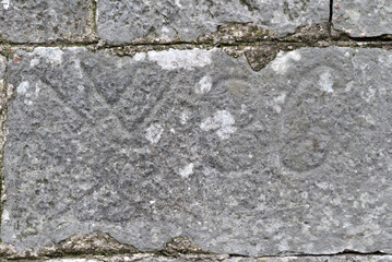Old Worn and Weathered Numbers Carved into Old Stone Block 